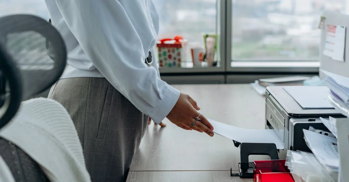 Professionnelle imprimant un document dans un environnement de bureau.