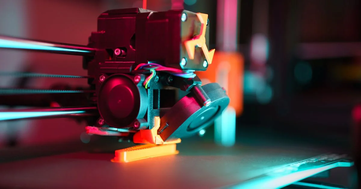 Gros plan d'une imprimante 3D en action avec un éclairage néon, mettant en valeur la technologie dans le prototypage.