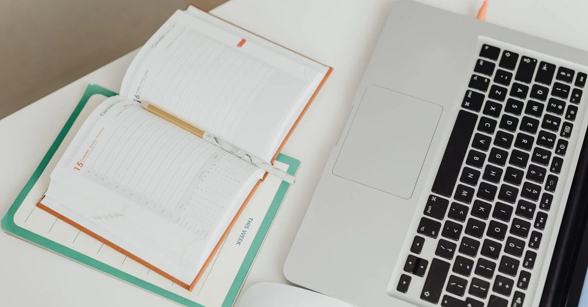 Vue du dessus d'un espace de travail propre avec un ordinateur portable, un cahier et une souris sur un bureau.